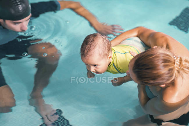 Madre con bebé niño e instructor de natación masculino en piscina . - foto de stock