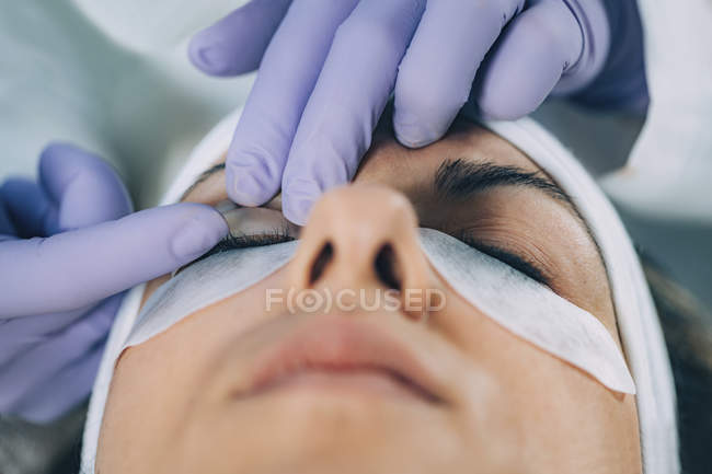 Cosmetologue effectuant un lifting des cils sur la patiente dans le salon . — Photo de stock