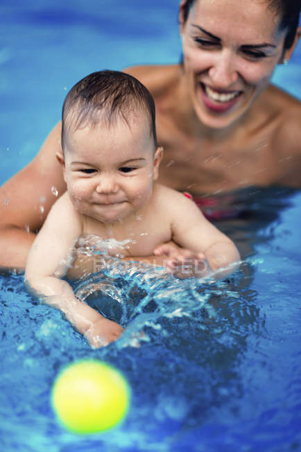 Mère jouant avec bébé garçon dans la piscine . — Photo de stock