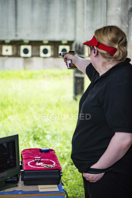 Mujer adulta practicando tiro con pistola deportiva . - foto de stock