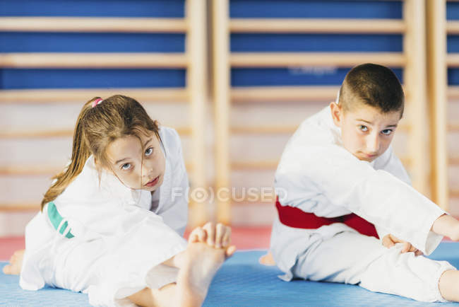 Menino e menina se alongando na aula de taekwondo . — Fotografia de Stock