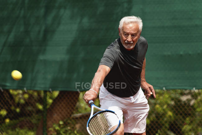 Seniorspieler übt Tennis auf dem Platz. — Stockfoto