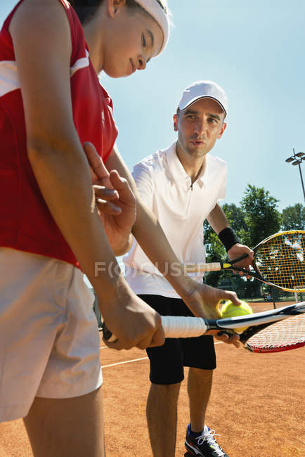 Jugador de tenis adolescente en entrenamiento con entrenador masculino . - foto de stock
