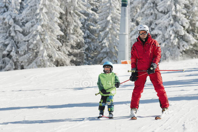 Aula de esqui com instrutor masculino e menino em montanhas nevadas . — Fotografia de Stock