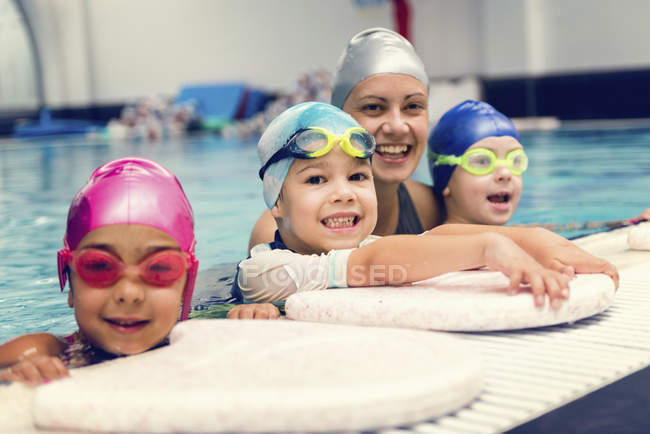 Crianças com instrutor de natação se divertindo na borda da piscina . — Fotografia de Stock