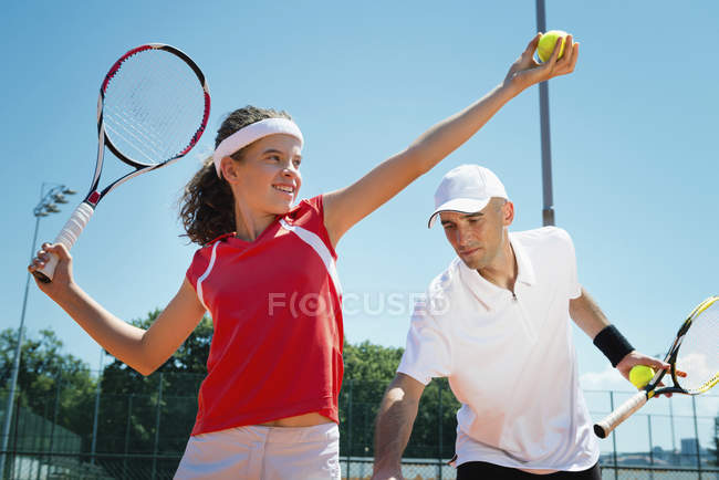Tennis instructor polishing serving posture with student. — Stock Photo