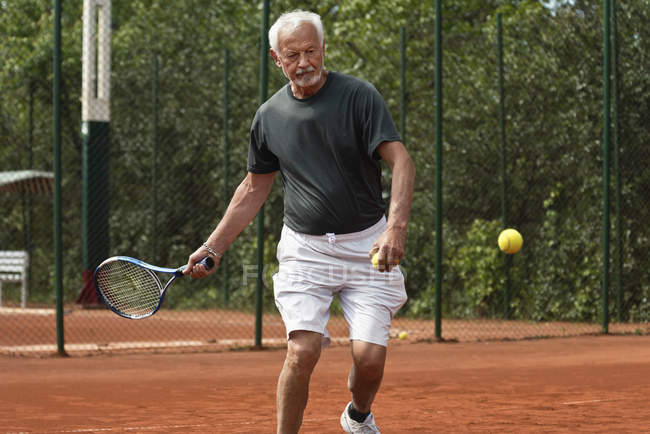 Joueur senior masculin pratiquant le tennis sur le court . — Photo de stock
