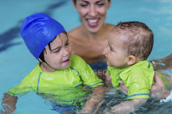 Lindos niños pequeños con madre en la piscina . - foto de stock