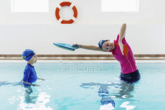 Мальчик на уроке плавания с инструктором в бассейне . — стоковое фото