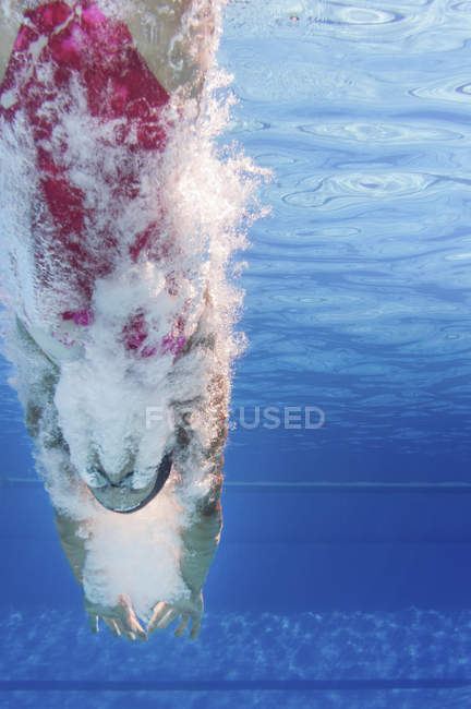 Female swimmer diving into public swimming pool water. — Stock Photo