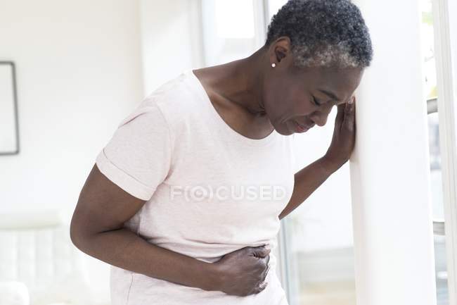 Mujer madura tocando el estómago en el dolor . - foto de stock