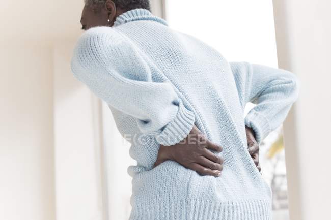 Mujer madura con dolor de espalda doblando hacia adelante . - foto de stock