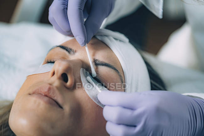 Cosmetologue nettoyage des yeux de la femme après la procédure de levage des cils — Photo de stock