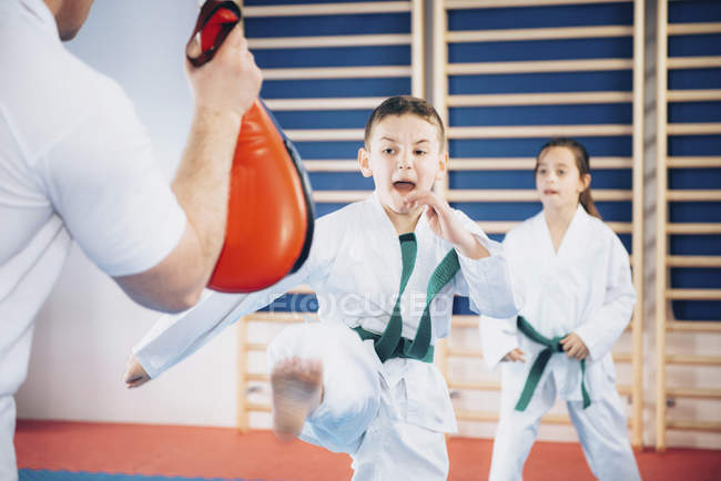 Crianças em idade elementar na aula de taekwondo com treinador . — Fotografia de Stock