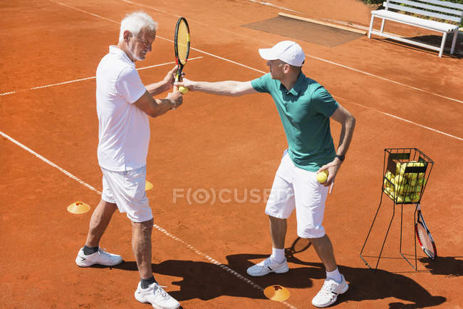 Старший мужчина на уроке тенниса с инструктором . — стоковое фото