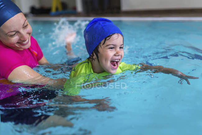 Niño pequeño teniendo clase de natación con instructor femenino en la piscina . - foto de stock