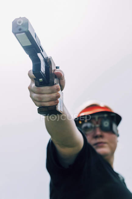Mulher adulta média praticando tiro pistola esportes . — Fotografia de Stock