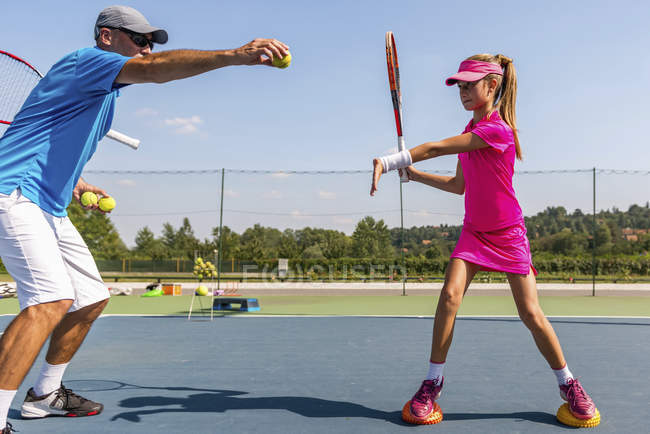 Chica adolescente en el entrenamiento de tenis en la cancha con instructor masculino . - foto de stock