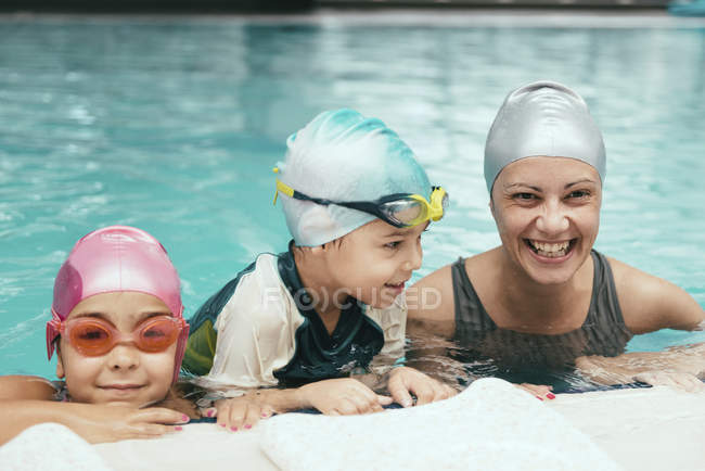 Дети с инструктором по плаванию веселятся на краю бассейна . — стоковое фото