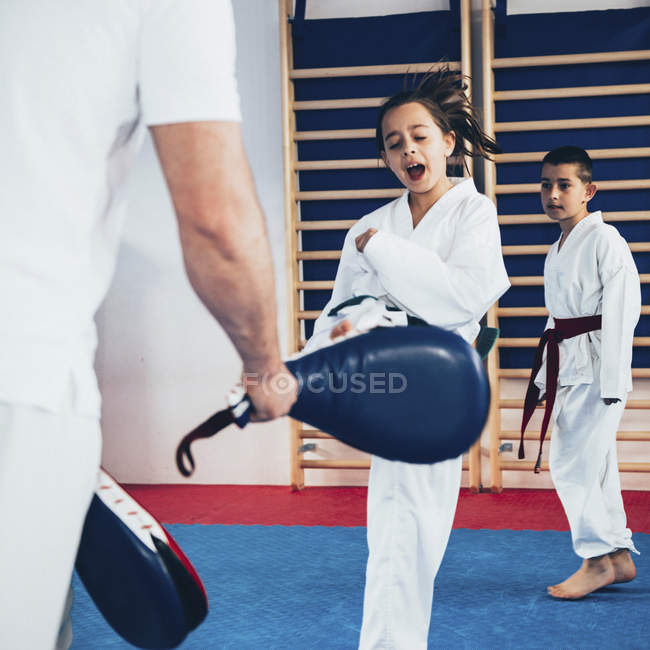 Instrutor de Taekwondo treinando menino e menina na classe . — Fotografia de Stock