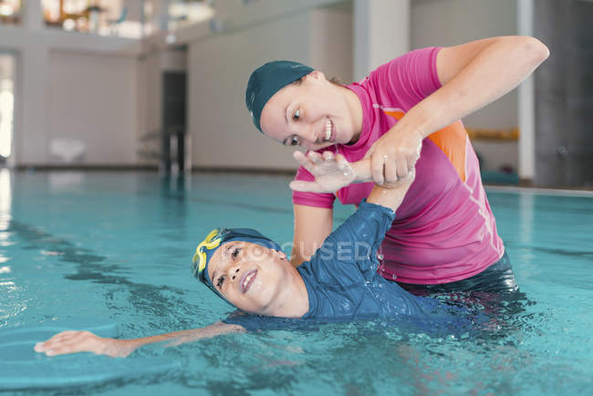 Ragazzo in classe di nuoto con istruttrice donna in piscina . — Foto stock