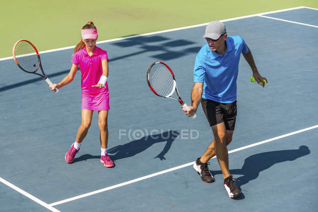 Teenage tennis player training with male coach on tennis court. — Stock Photo