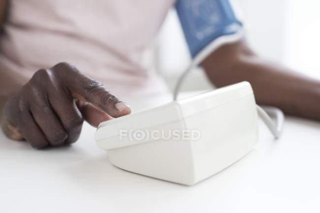 Close-up of hand of mature woman testing blood pressure with machine. — Stock Photo