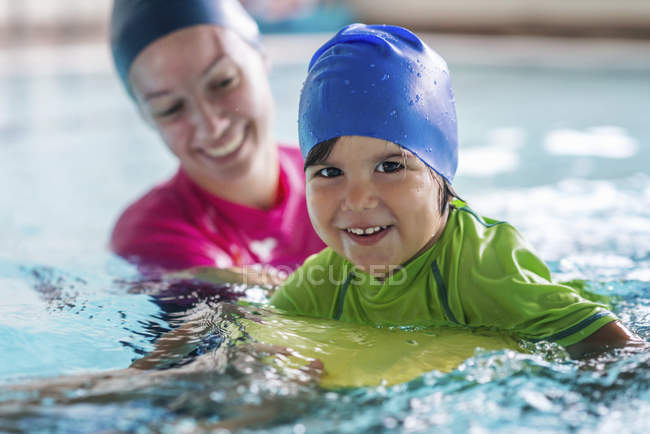 Menino aprendendo a nadar com instrutor na piscina . — Fotografia de Stock