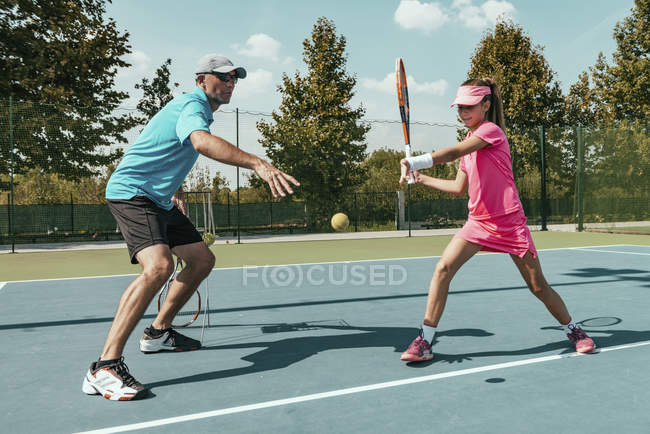 Tennis instructor training adolescent girl in summer. — Stock Photo