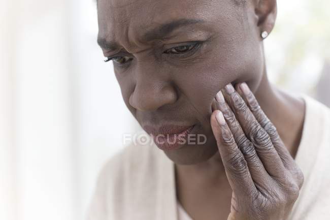 Mujer madura con dolor de muelas tocando la cara . - foto de stock