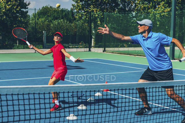 Tenista adolescente practicando con instructor masculino en clase de tenis . - foto de stock