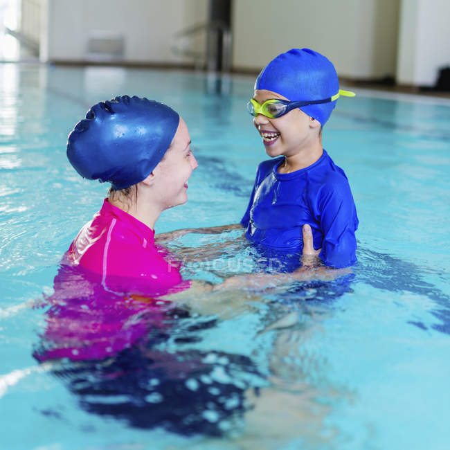Милый мальчик веселится с инструктором по плаванию в бассейне . — стоковое фото
