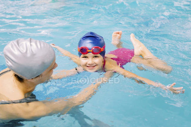 Niña aprendiendo a nadar con instructor en piscina pública . - foto de stock