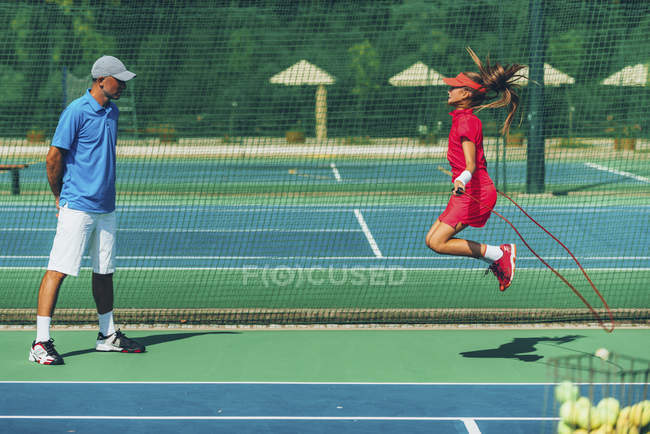 Teen girl jumping rope with tennis coach. — Stock Photo