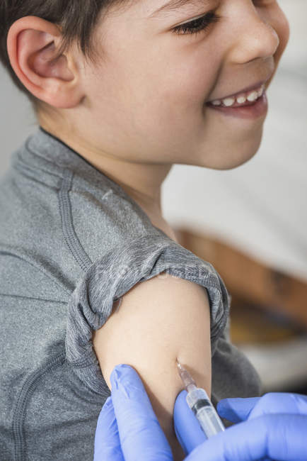 Un niño recibe una vacuna en el consultorio médico. . - foto de stock