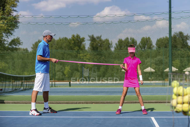 Adolescente ragazza in allenamento di tennis con banda di resistenza con allenatore
. — Foto stock