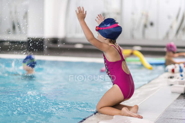 Kleines Mädchen planscht Wasser neben öffentlichem Schwimmbad. — Stockfoto