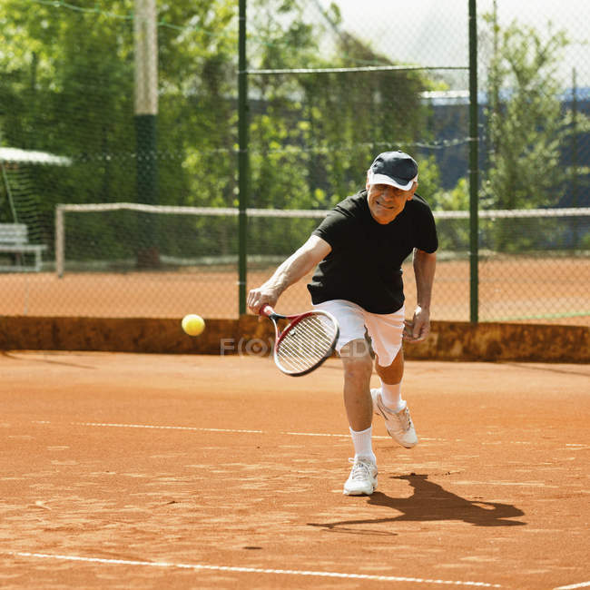 Active senior player practicing tennis on court. — Stock Photo