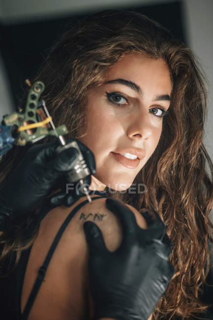 Joven mujer consiguiendo hombro tatuaje . - foto de stock
