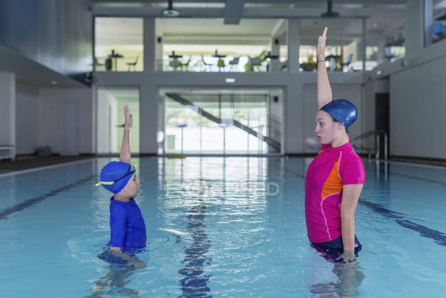 Bonito menino aprendendo a nadar com instrutora na piscina . — Fotografia de Stock