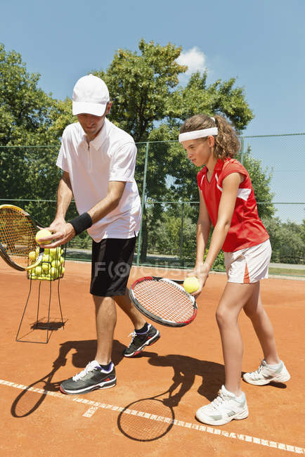 Tennis instructor working with teenage girl on court. — Stock Photo