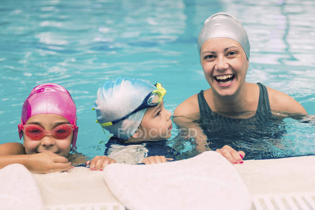 Веселый инструктор по плаванию, развлекающийся с детьми во время урока в бассейне . — стоковое фото