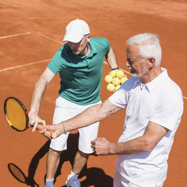 Hombre mayor que tiene clase de tenis con instructor masculino . - foto de stock