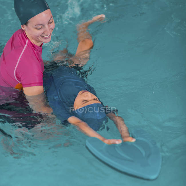 Ragazzo in classe di nuoto con istruttore in piscina . — Foto stock