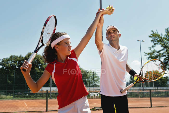 Jugendliches Mädchen serviert Tennisbälle im Tennisunterricht. — Stockfoto