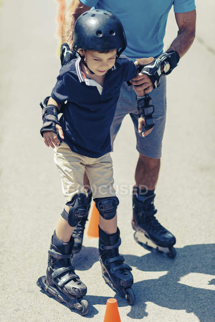 Senior teacher of rollerskating with boy practicing on class in park. — Stock Photo