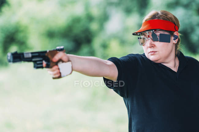 Mulher adulta média praticando tiro pistola esportes . — Fotografia de Stock