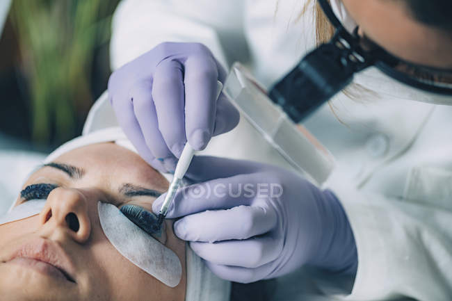 Косметолог Одягаючи чорну фарбу на вії пацієнта під час підйому і ламінацією. — стокове фото