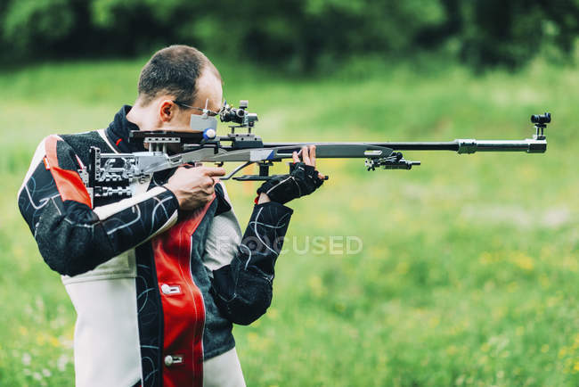 Hombre adulto practicando tiro con rifle deportivo
. - foto de stock