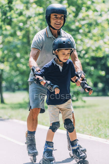 Opa und Enkel genießen Rollschuhlaufen im Sommerpark. — Stockfoto